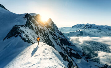 Mann spaziert über mit Schnee bedeckte Berge