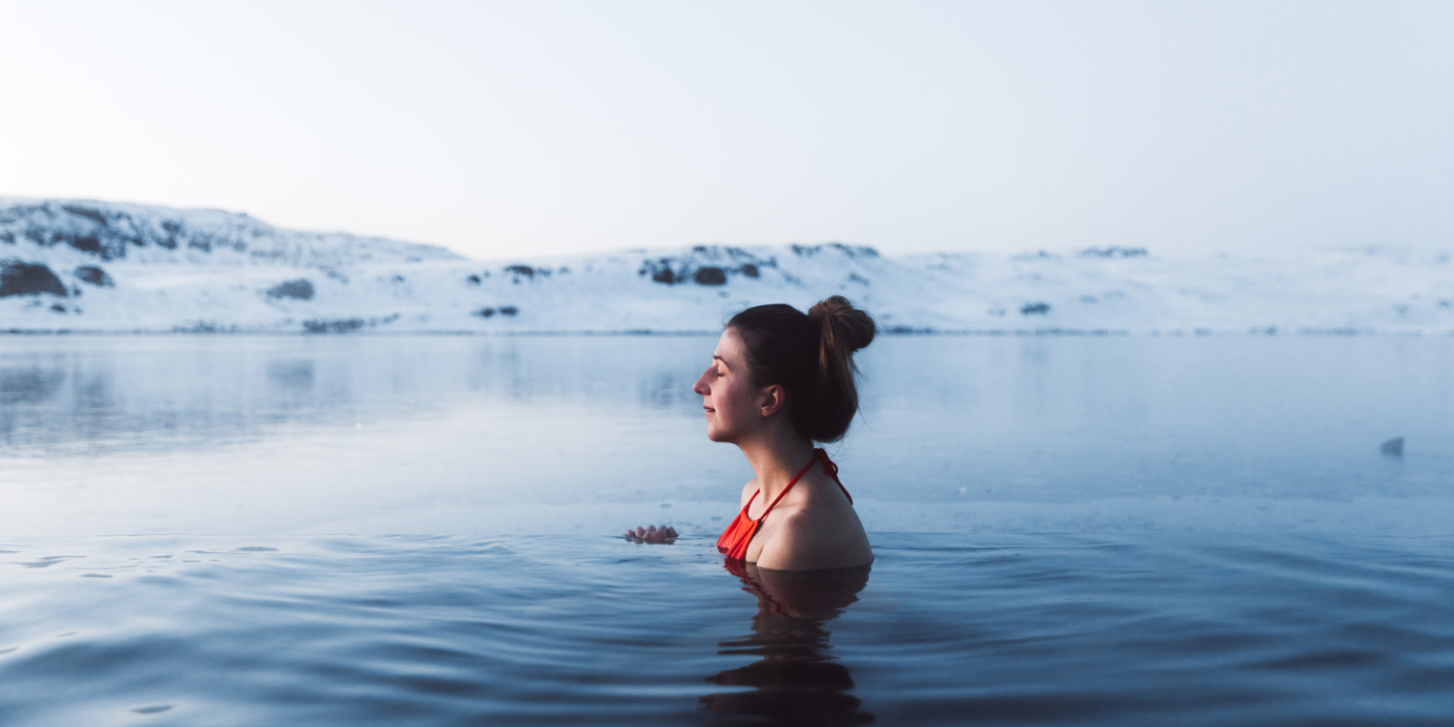 Frau ist glücklich beim Eisbaden in einem See
