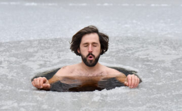 Mann hockt in einem Eisloch und atmet nach der Wim-Hof-Methode