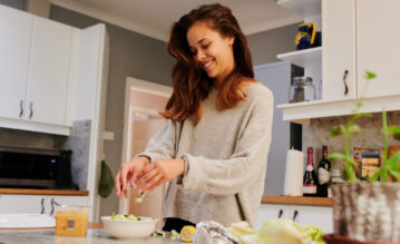 Junge Frau bereitet sich Essen in der Küche zu und fühlt sich wohl