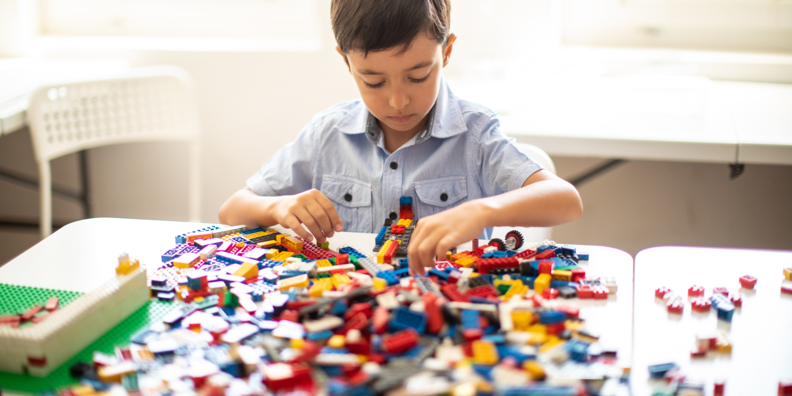 Kleiner Junge spielt mit Lego am Tisch