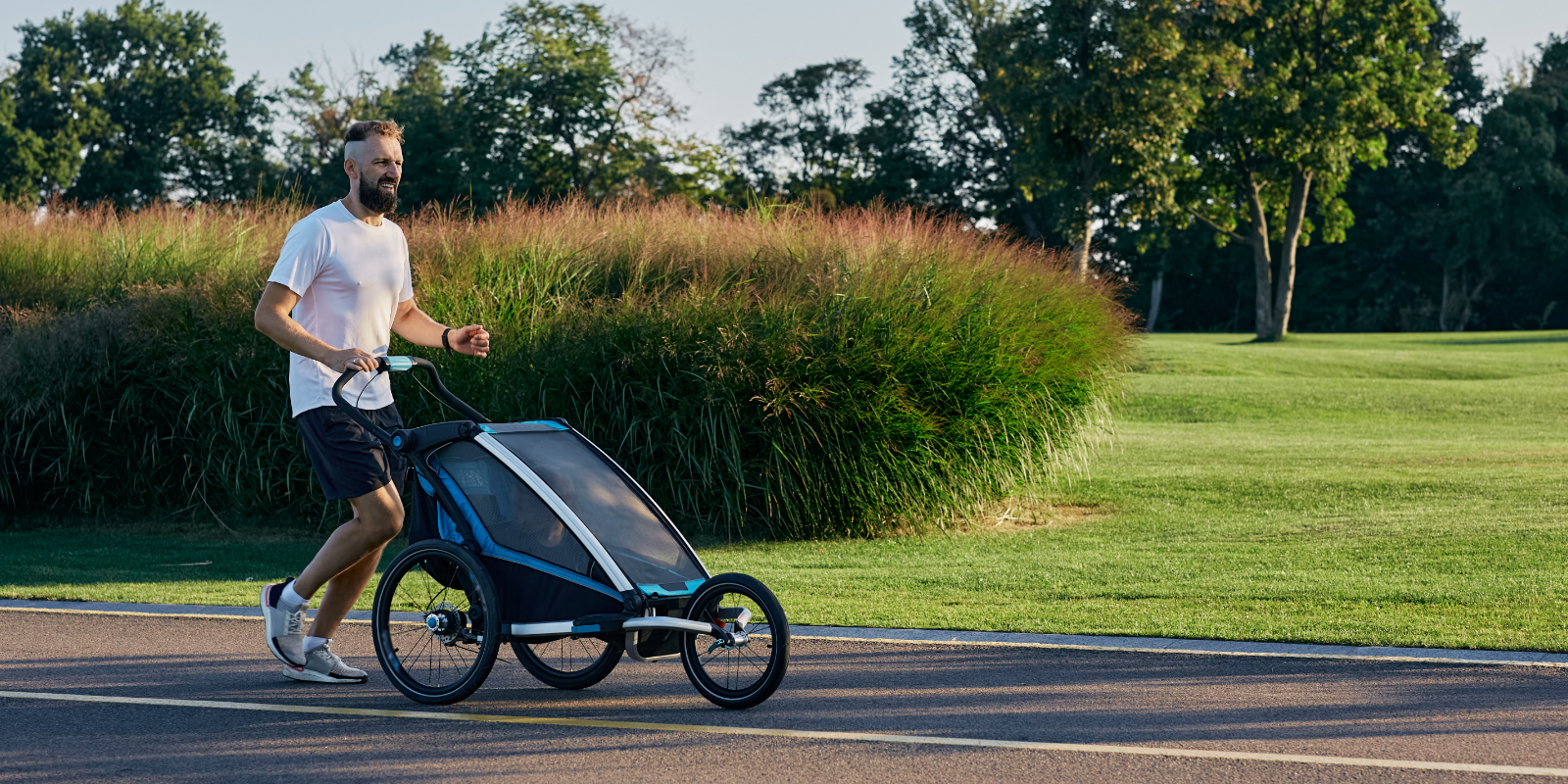 Vater joggt mit seinem Kind im Kinderwagen