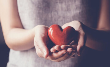 Frau hält rotes Herz in der Hand nach dem Blutspenden