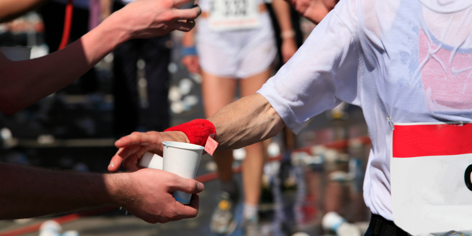 Frau bekommt während eines Marathons ein Getränk gereicht