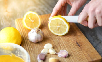 Frau schneidet Zitrone für ihre Zitronen-Knoblauch-Kur