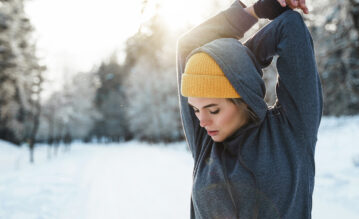 Frau stretcht sich beim Training im Winter.