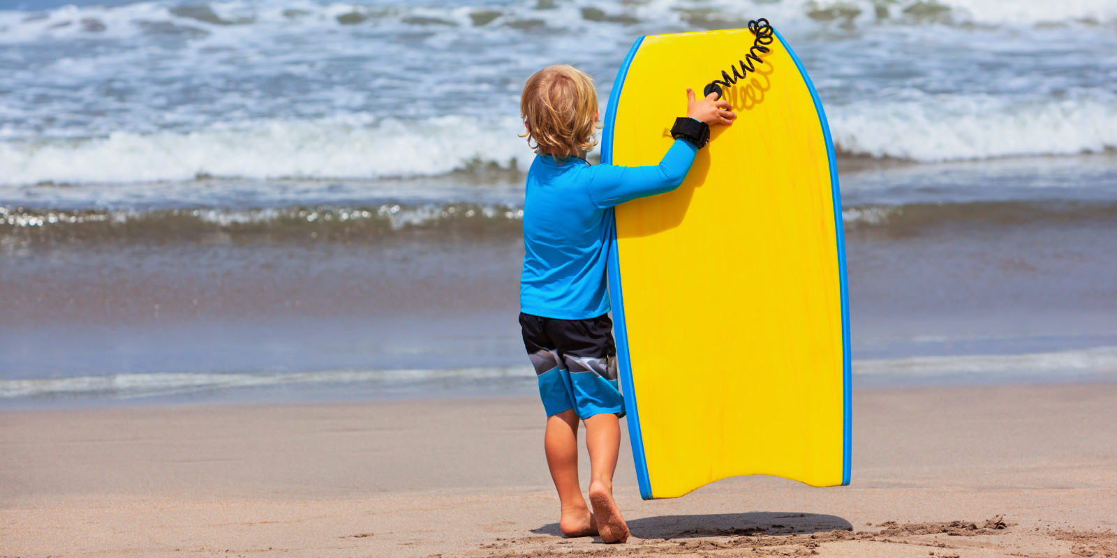 Kind läuft mit einem leichtem EPS-Bodyboard zum Strand