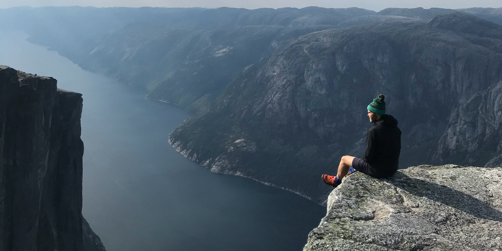 Julian Brandecker sitzt auf einer Klippe in den Bergen