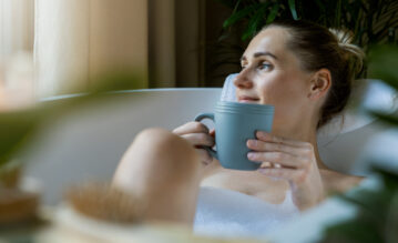 Frau nimmt ein Erkältungsbad und trinkt dabei einen Tee