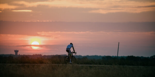 Lukas Kaufmann beim Radfahren neben einem Sonnenuntergang
