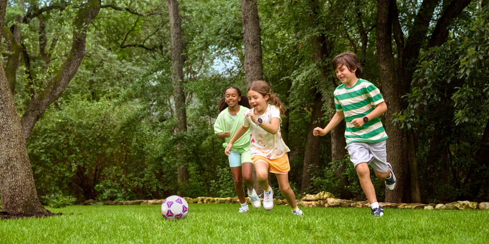 3 Kinder beim Fußball spielen auf dem Rasen