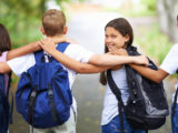 Kinder umarmen sich auf dem Weg zur Schule