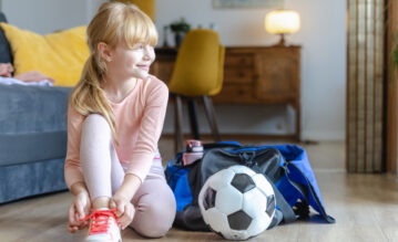 Kleines, blondes Mädchen schnürt ihre Sportschuhe