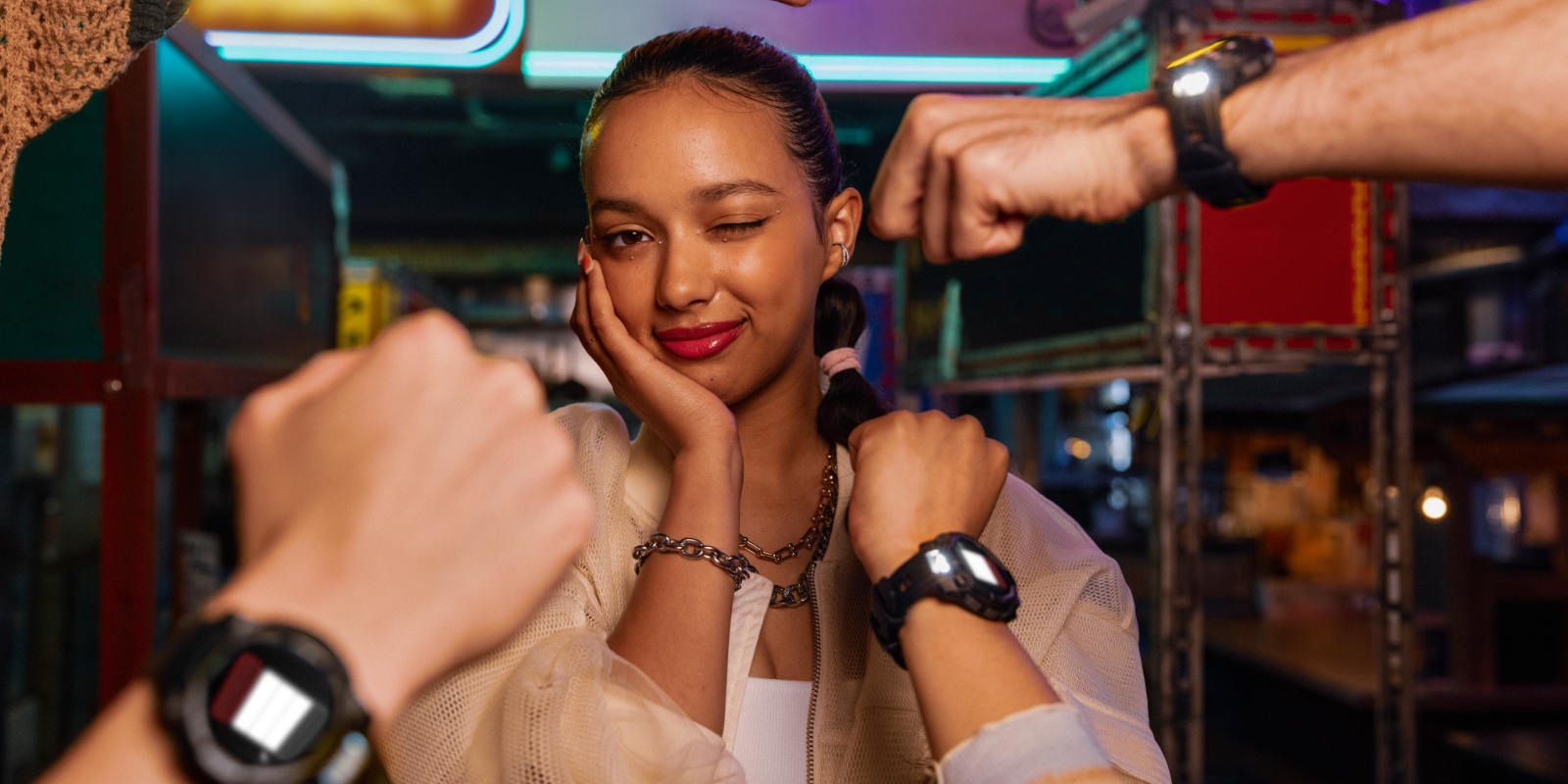 Junge Frau mit Instinct 3 von Garmin am Handgelenk sitzt mit Freunden in einer Bar