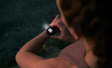 Eine Frau in Sportbekleidung trägt den neuen Forerunner 970 von Garmin am Handgelenk und nutzt die Funktion Taschenlampe in der Dunkelheit.