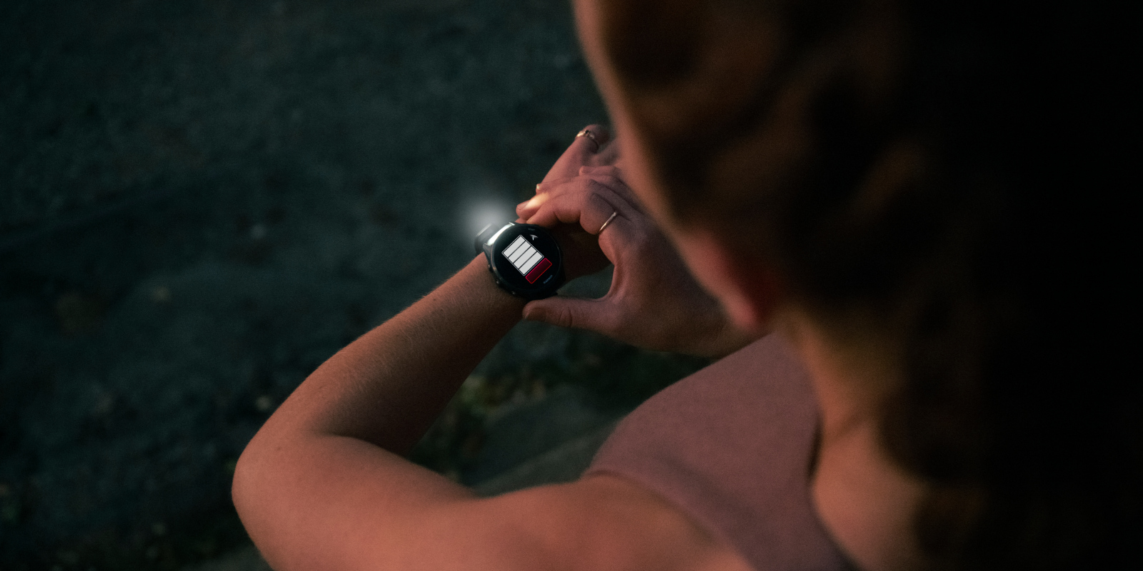 Eine Frau in Sportbekleidung trägt den neuen Forerunner 970 von Garmin am Handgelenk und nutzt die Funktion Taschenlampe in der Dunkelheit.