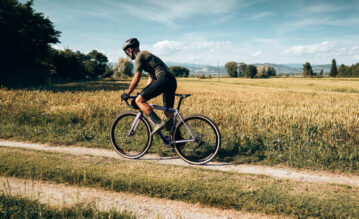 Mann fährt mit Helm auf seinem Gravel Bike über einen Feldweg