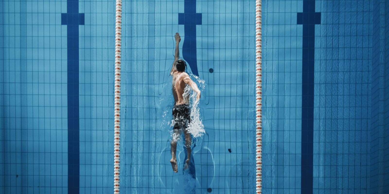 Ein Mann schwimmt in einer Schwimmhalle im Kraulstil.