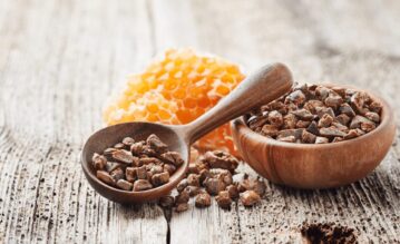 Ein Holzlöffel und ein Schälchen mit Propolis darin.