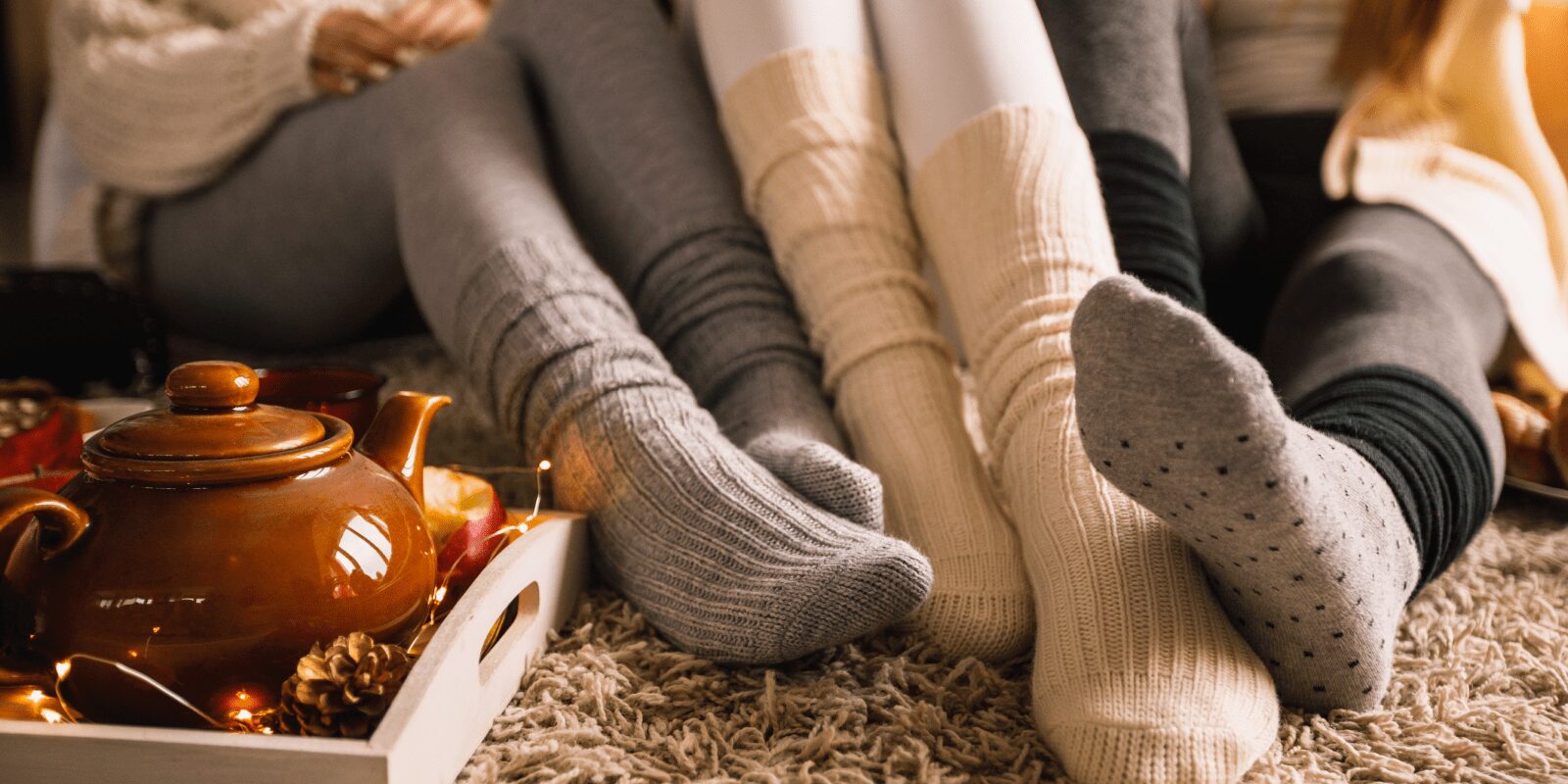 Füße in warmen Wollsocken auf einem flauschigen Teppich.