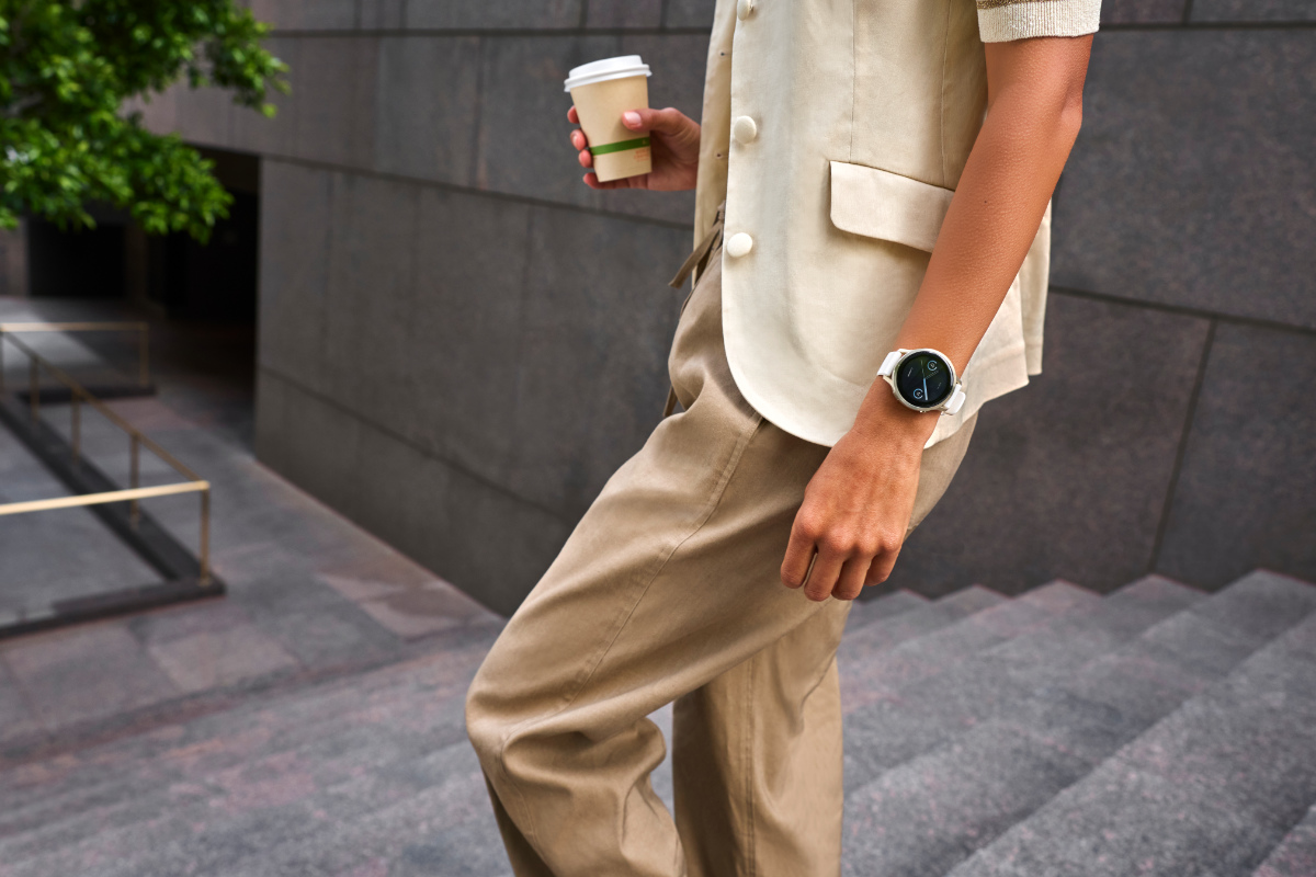 Mann mit einem Kaffeebecher in der Hand und der Garmin Venu 4 am Handgelenk geht eine Treppe hinunter