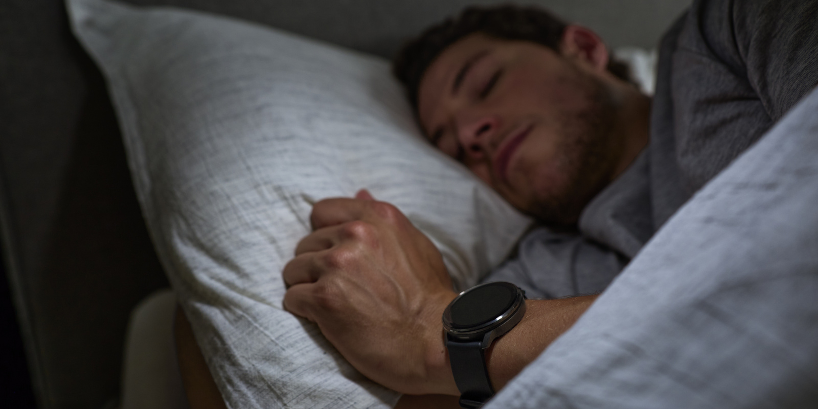 Mann mit Garmin Venu 4 am Handgelenk liegt im Bett und schläft