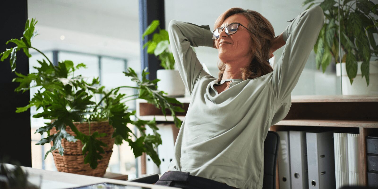 Eine Frau lehnt sich in ihrem Bürostuhl zurück und entspannt.