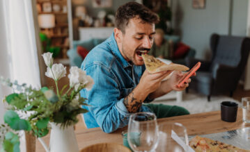 Mann beißt genüsslich in eine Pizza zuhause